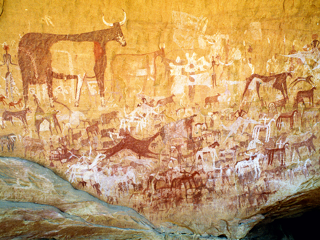 Richly decorated panel of paintings in northern Chad from the pastoral period of Saharan rock art. Images include decorated cattle, mounted camels, horses and warriors