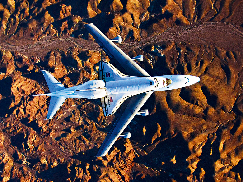Space shuttle Endeavour, mounted on top of a modified Boeing 747 carrier aircraft, flies over the Mojave Desert